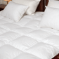 a bed with white goose down comforter and down pillows
